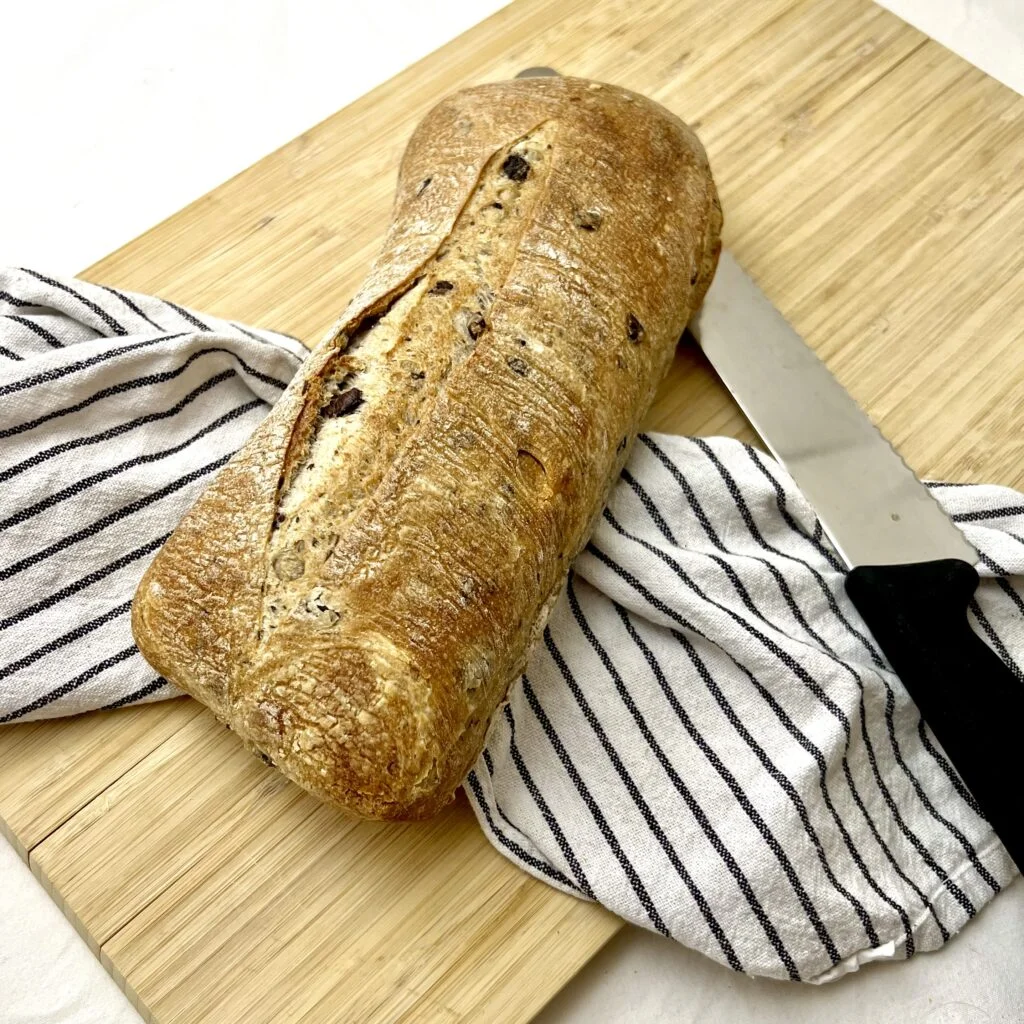 Brot ohne Hefe mit Backpulver braun auf weiss grau gestreiftem tuch auf hellbraunem holzbrett neben brotmesser
